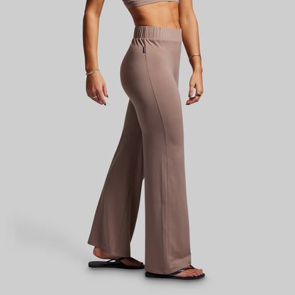 Person wearing brown wide-leg pants on a gray background