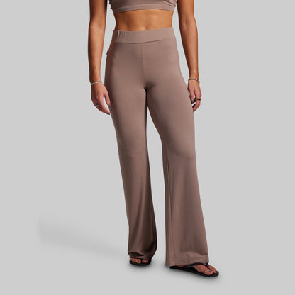 Person wearing brown high-waisted pants on a gray background