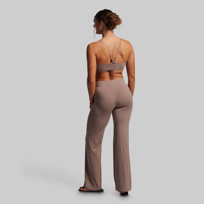 Woman wearing a beige sports bra and pants on a gray background