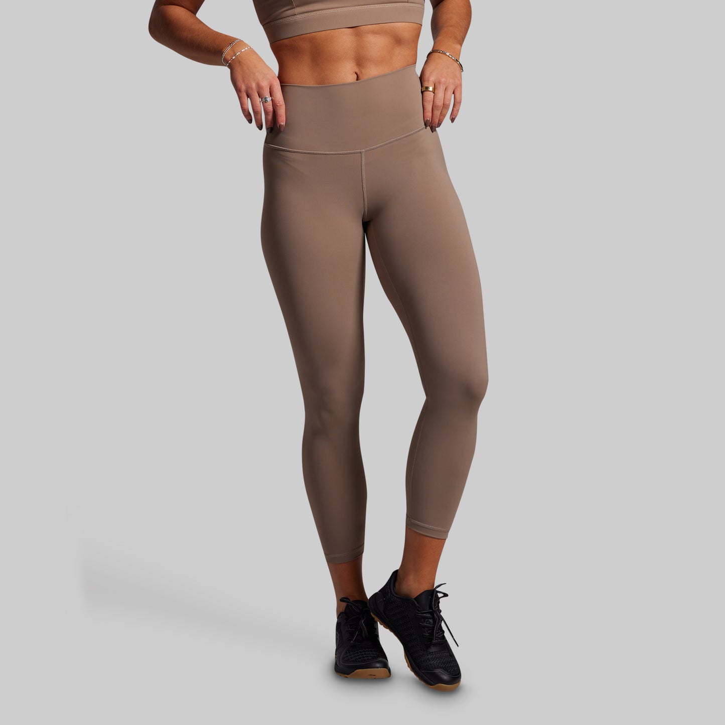 Person wearing beige leggings and a matching top on a gray background