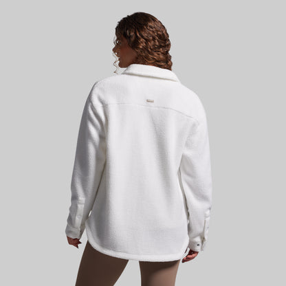 Person wearing a white fleece jacket on a plain background