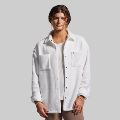 Woman wearing a white textured shirt over a plain shirt on a gray background
