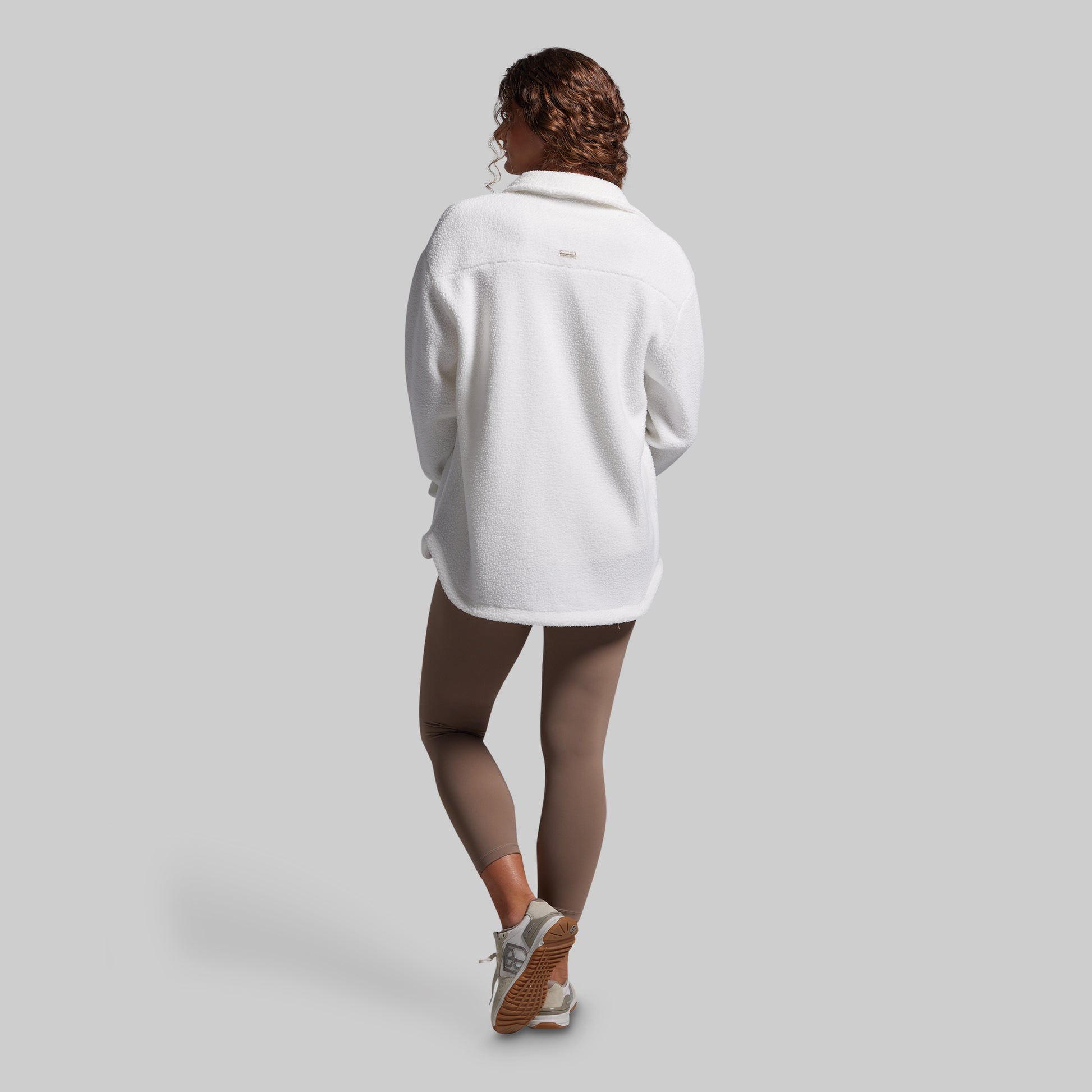 Person wearing a white oversized sweater on a plain background