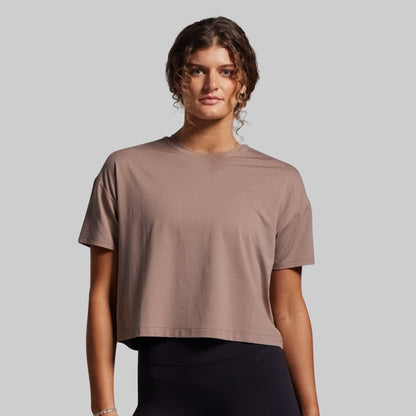 Woman wearing a brown t-shirt against a plain background