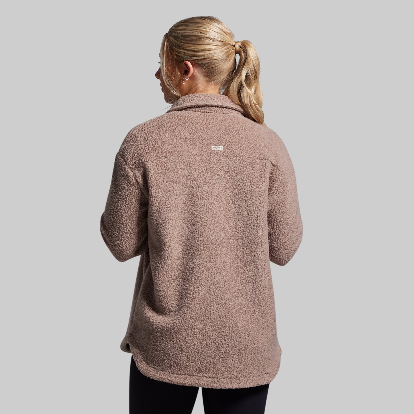 Person wearing a brown fleece jacket on a plain background