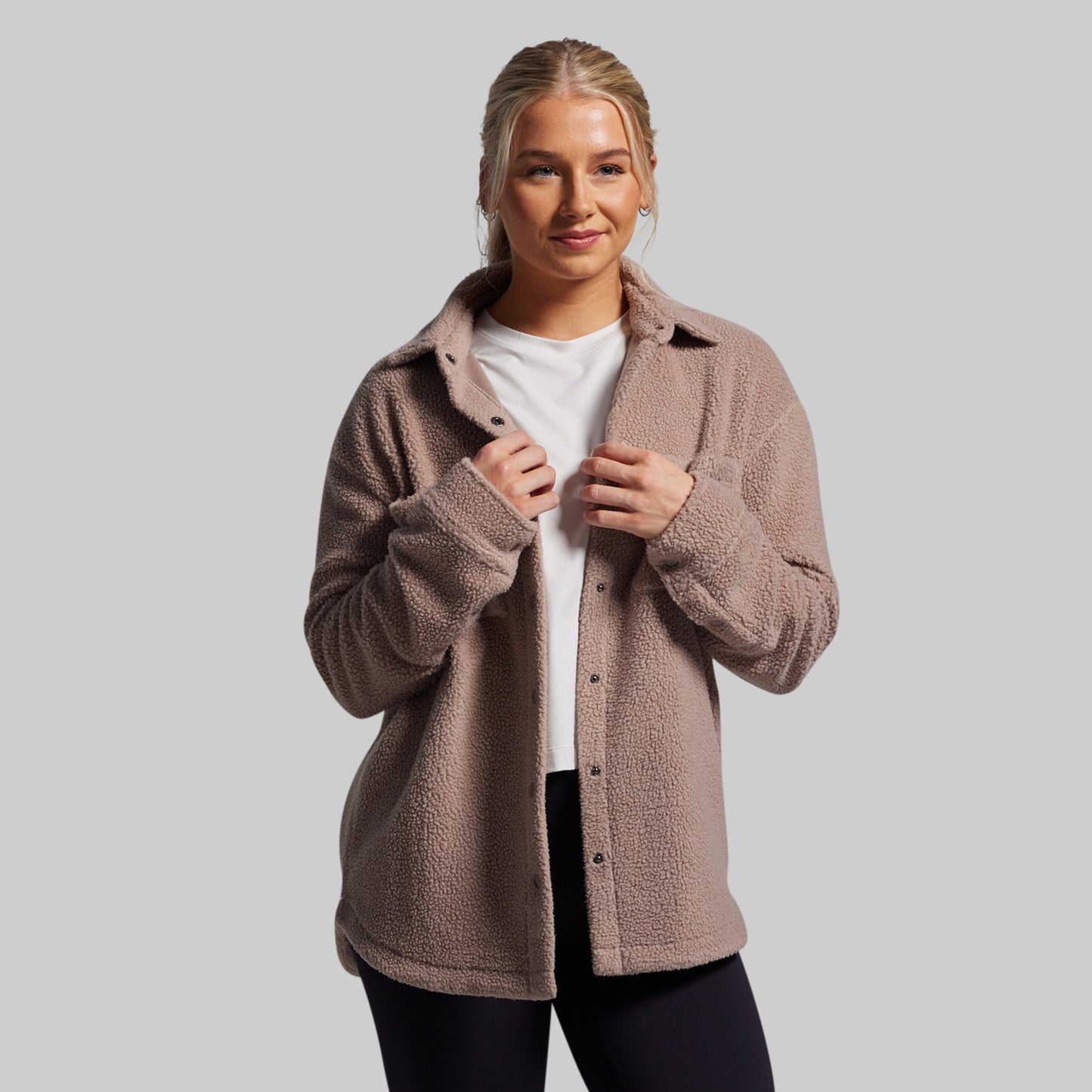Woman wearing a brown fleece jacket on a gray background