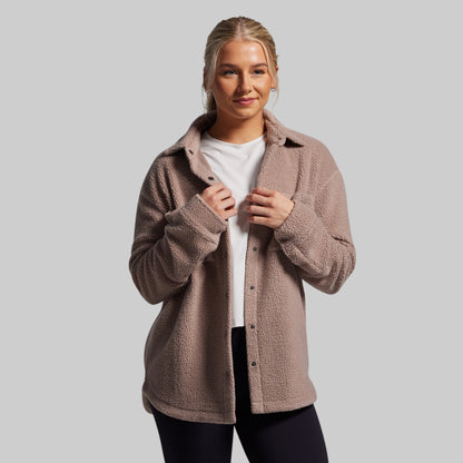 Woman wearing a brown fleece jacket on a gray background