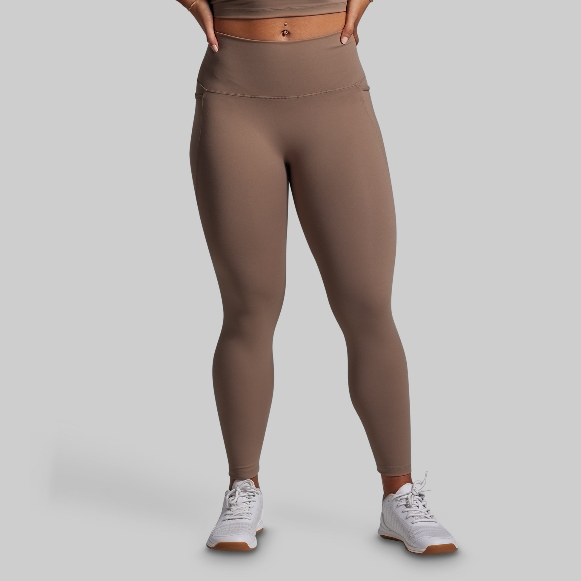 Person wearing brown leggings on a gray background