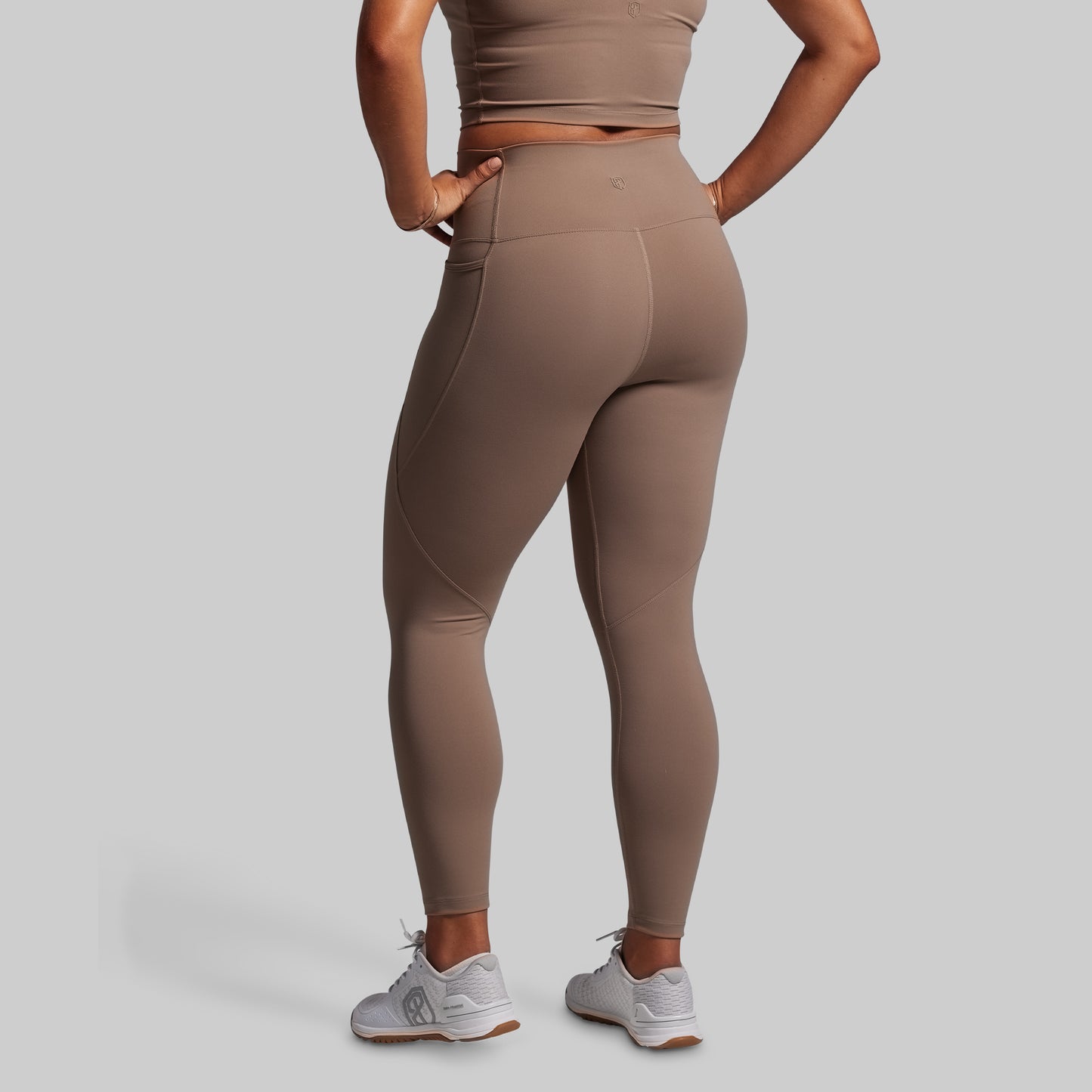 Person wearing beige leggings and a matching top on a plain background