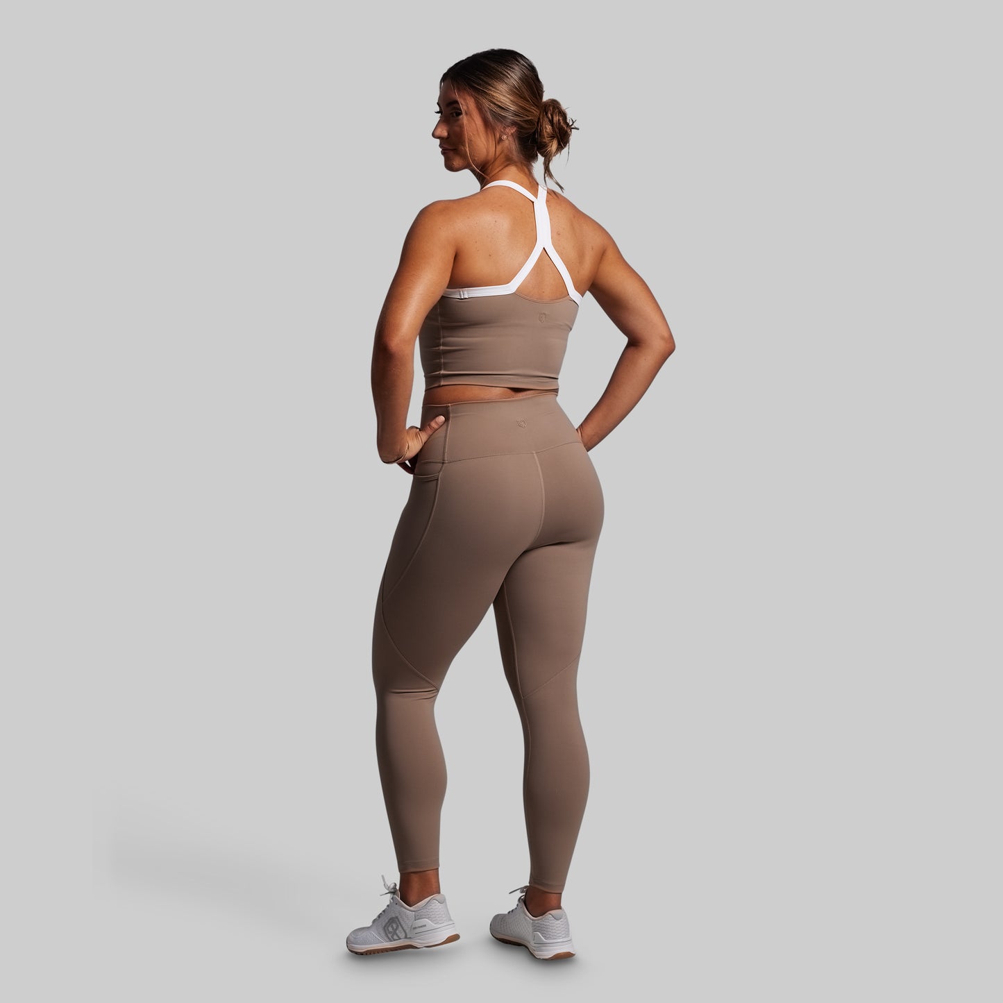 Woman wearing a brown athletic outfit on a gray background