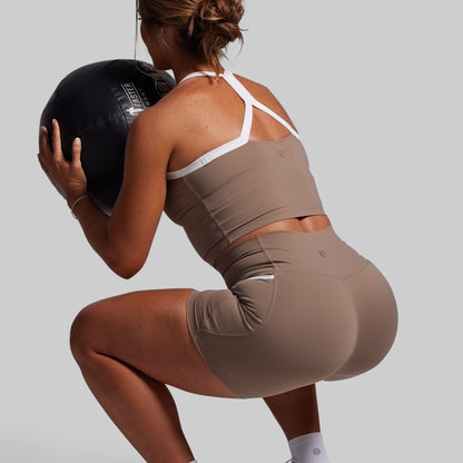 Person in brown athletic wear holding a medicine ball against a plain background