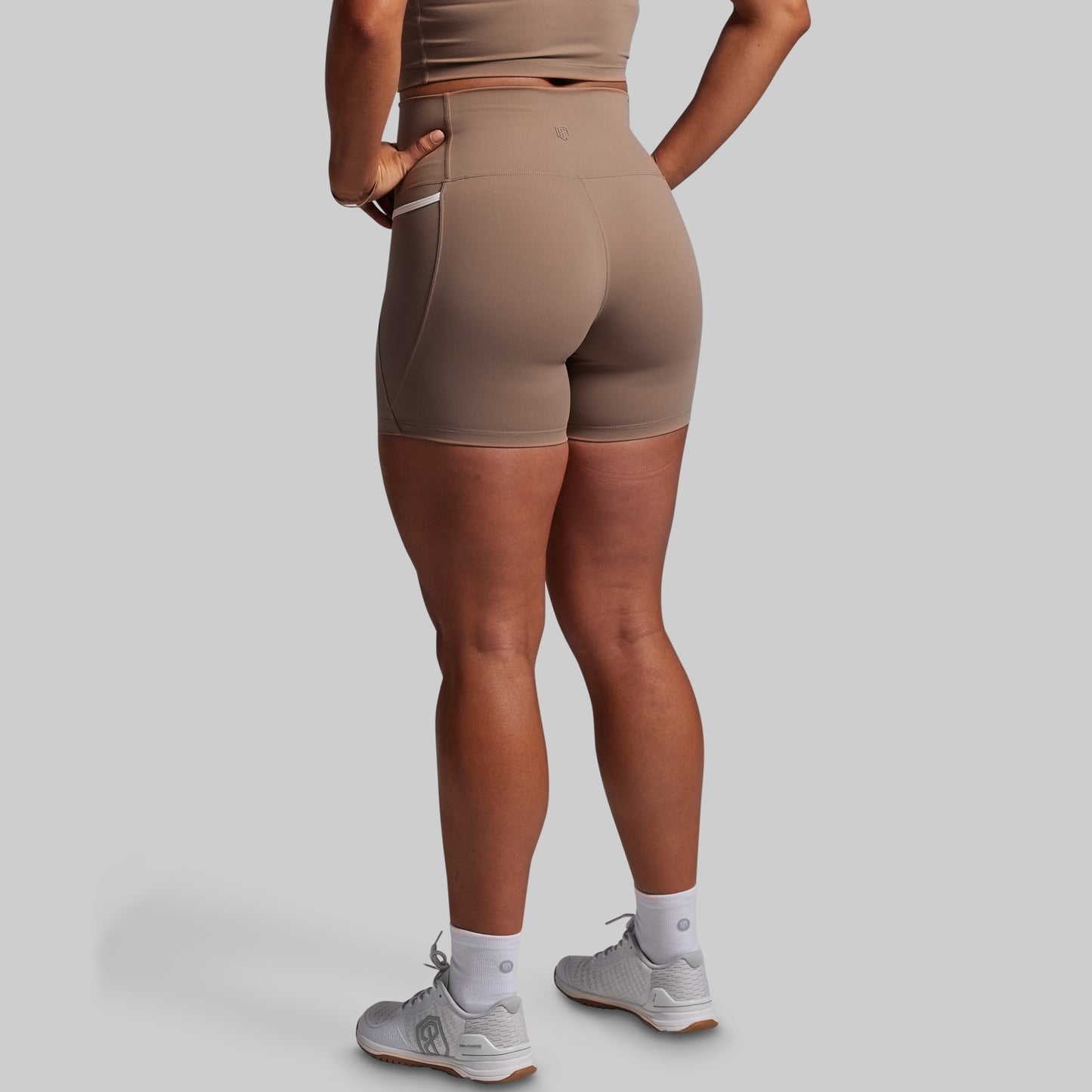Person wearing brown high-waisted shorts on a gray background