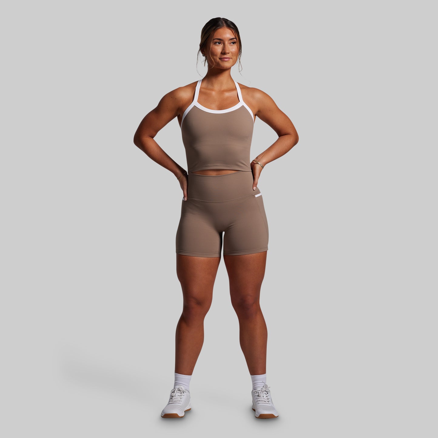 Woman wearing a brown athletic outfit on a gray background