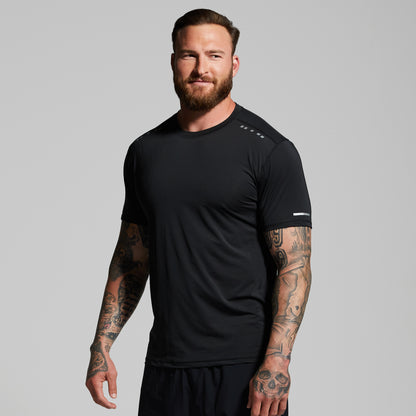 Man wearing a black athletic shirt with visible tattoos on arms against a gray background